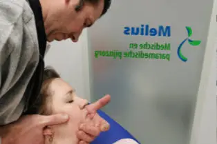 De therapeut voert mobilisatietechniek uit bij nekklachten door gebruik te maken van manuele therapie.