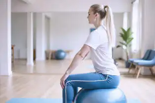 Patiënt voert zelfstandig bewegingsagogische oefening uit op een balansbal.