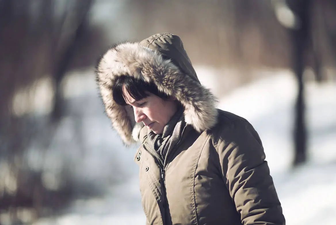 Persoon die in de winter buiten loopt met dikke jas aan, als illustratie van nek- en schouderklachten in de winter