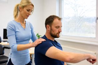 Therapeut begeleidt patiënt bij schouderoefening voor herstel na blessure.